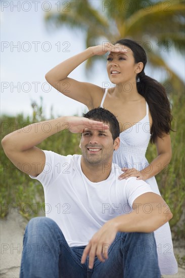 Hispanic couple shielding eyes from sun