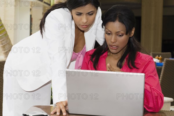 Hispanic businesswomen looking at laptop