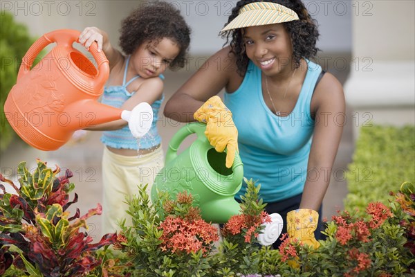 African mother and daughter watering flowers