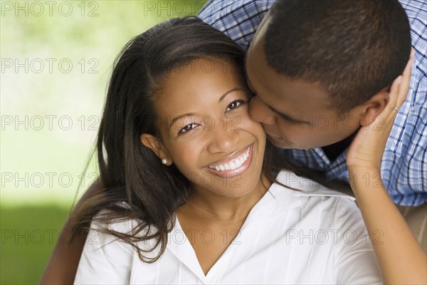 African man kissing wife's cheek