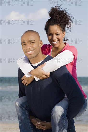 African man giving girlfriend piggy back ride