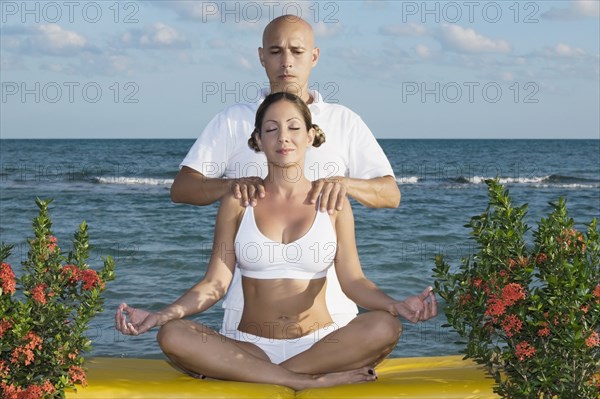 Hispanic man massaging meditating woman