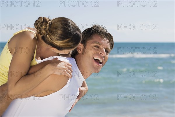 Hispanic man giving girlfriend piggy back ride