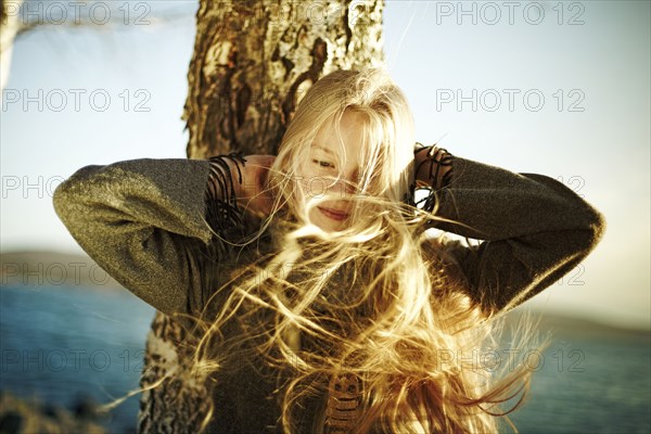 Caucasian girl's hair being blown by the wind near ocean