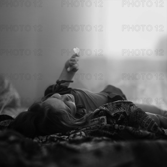Caucasian girl laying on blanket with butterfly on finger