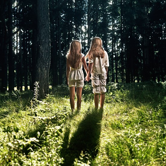 Caucasian girls holding hands in forest