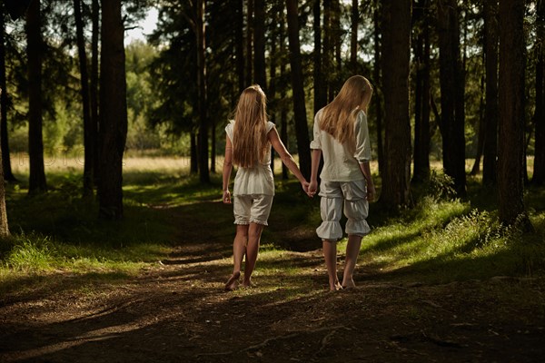 Caucasian girls holding hands in forest