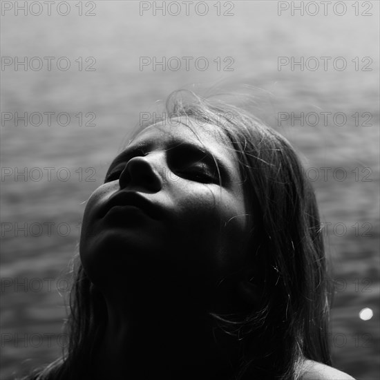 Caucasian girl with head back by lake