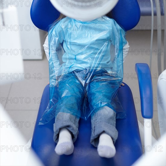 Caucasian girl wearing plastic sheet at dentist