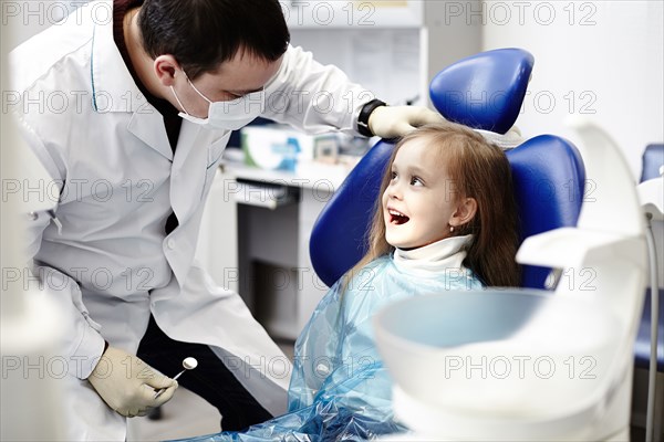 Caucasian dentist examining girl's teeth