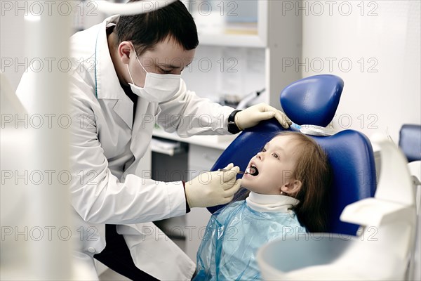 Caucasian dentist examining girl's teeth