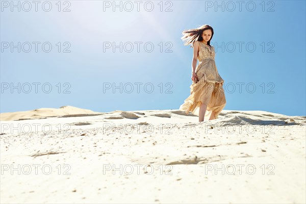 Caucasian woman walking on sand dune hill