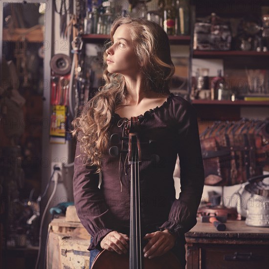 Caucasian teenage girl holding musical instrument in workshop