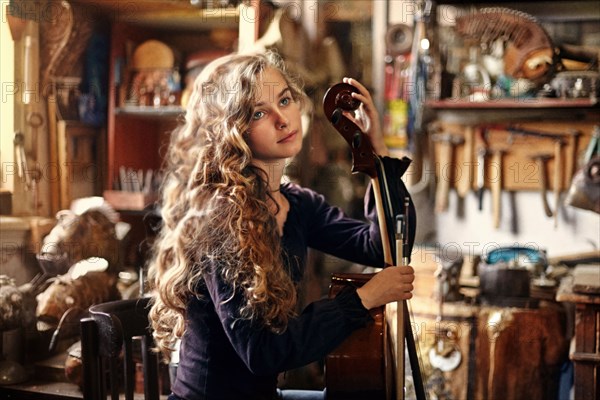 Caucasian teenage girl holding musical instrument in workshop