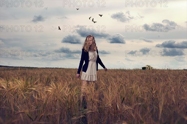 Caucasian teenage girl standing in field of tall grass