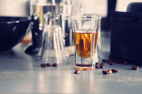 Close up of shot glass with coffee beans on table