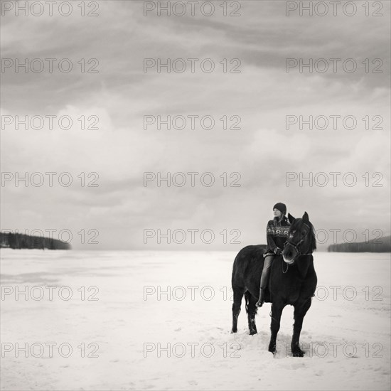 Caucasian girl riding horse in snowy field