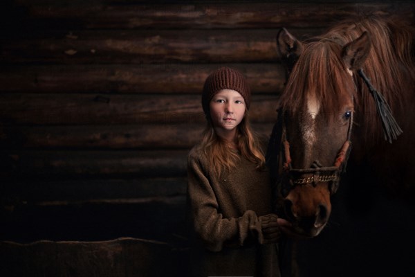 Caucasian girl standing with horse in barn