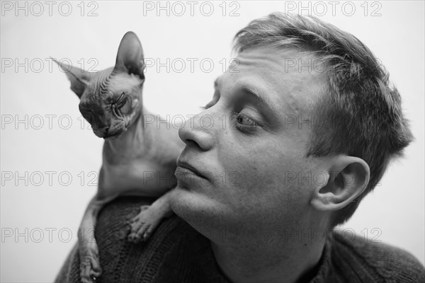 Hairless cat sitting on shoulder of Caucasian man