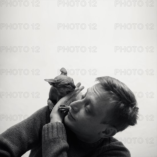 Caucasian man playing with hairless cat on shoulder