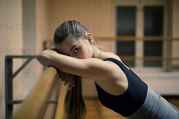 Caucasian dancer leaning on barre in studio