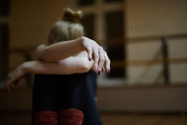 Fatigued Caucasian dancer sitting on studio floor