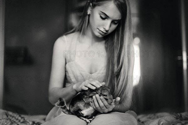 Caucasian girl holding pet chinchilla on bed