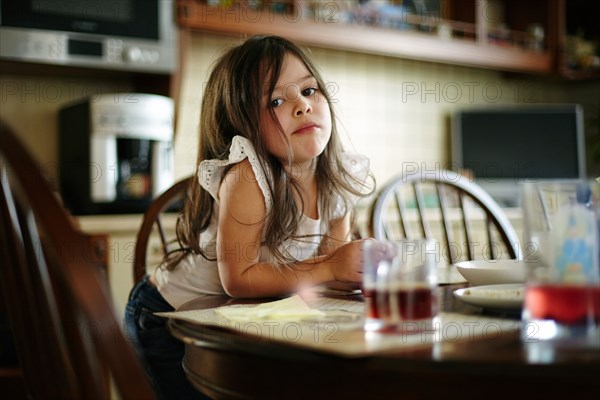 Caucasian girl eating at kitchen table