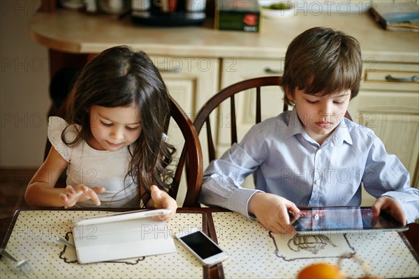 Caucasian brother and sister using digital tablets