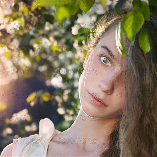 Caucasian teenage girl standing under tree