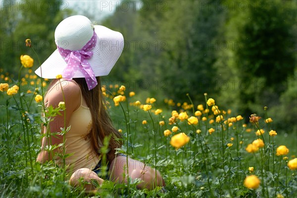 Caucasian teenage girl sitting in field with flowers