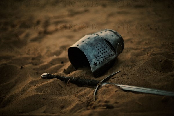 Medieval helmet and sword in sand