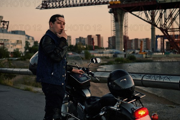 Caucasian man smoking near motorcycle