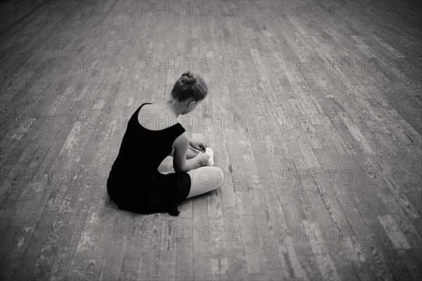 Caucasian ballerina tying pointe shoes