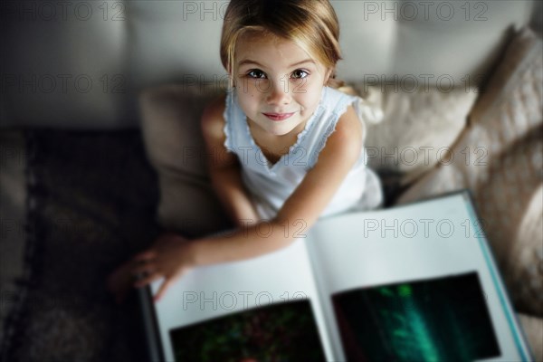 Caucasian girl reading book on sofa