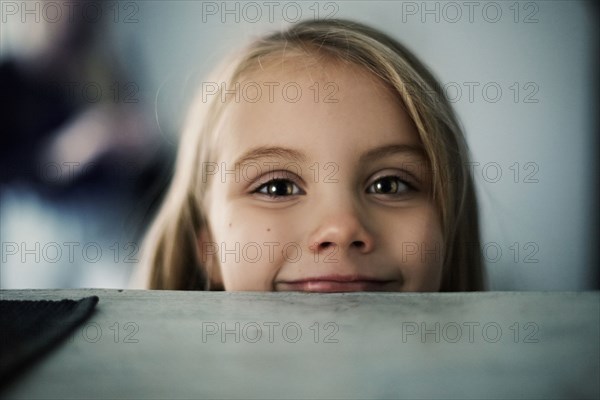 Caucasian girl peering over counter