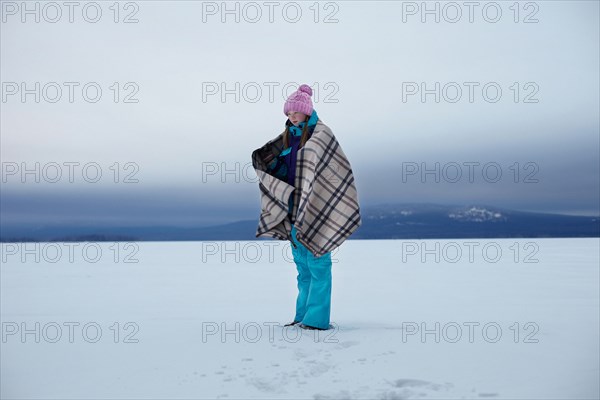 Caucasian teenage girl wrapped in blanket in snow