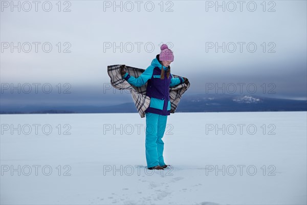 Caucasian teenage girl wrapped in blanket in snow