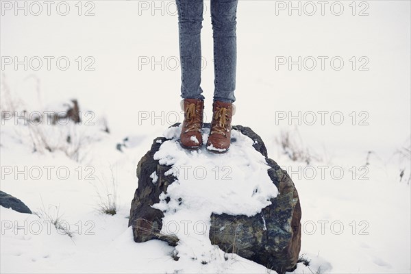 Caucasian teenage girl standing on snowy rock