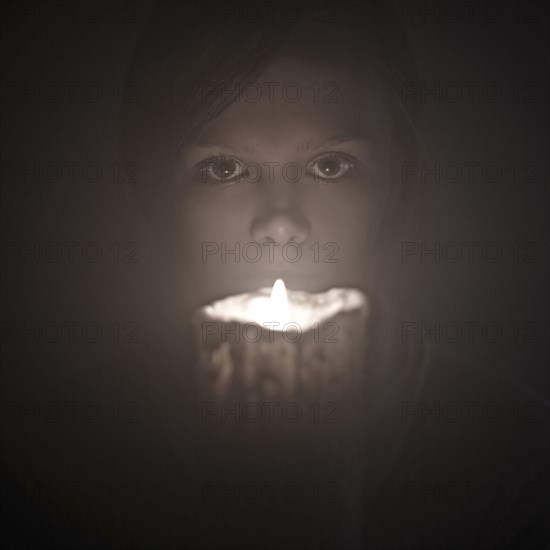 Caucasian woman holding candle near face