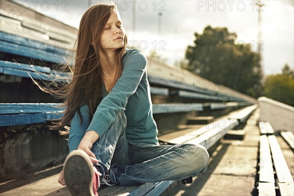 Caucasian woman sitting on bleachers