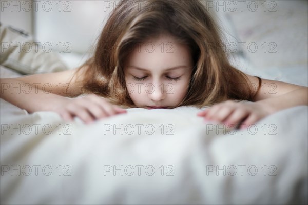 Caucasian teenage girl laying on bed