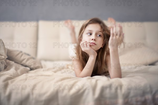 Caucasian teenage girl laying on bed