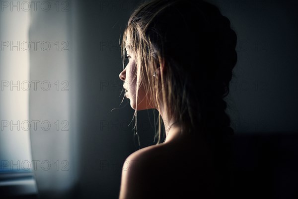 Caucasian teenage girl looking out window