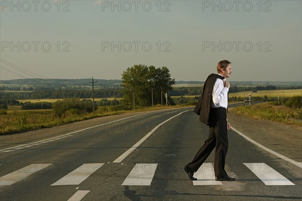 Caucasian businessman crossing rural street