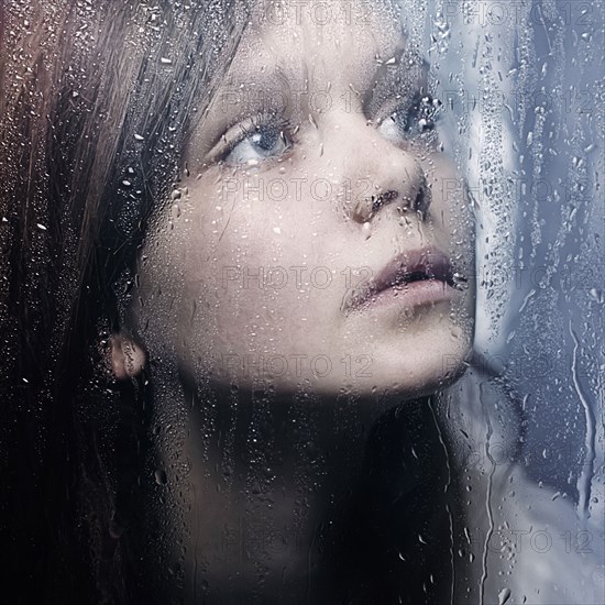 Caucasian woman standing at wet glass