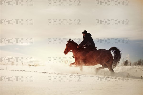 Caucasian man riding horse in snowy landscape