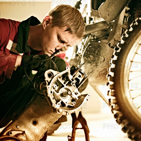 Caucasian mechanic examining motorcycle parts