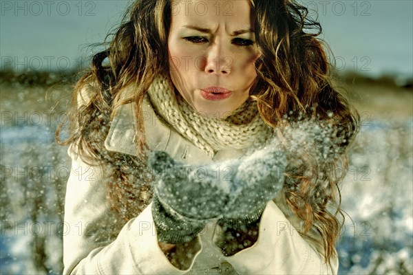 Caucasian woman blowing handful of snow