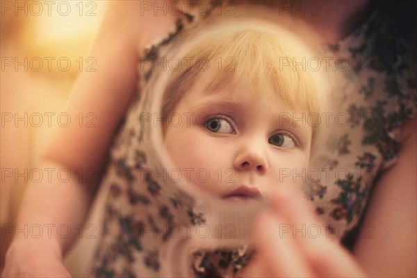 Caucasian preschooler girl examining herself in mirror